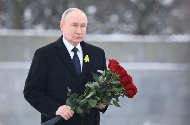 In this pool photograph distributed by the Russian state agency Sputnik, Russia's President Vladimir Putin lays flowers at the grave of his brother, who died as a child during the siege of Leningrad, during a ceremony at the Piskaryovskoye Memorial Cemetery in Saint Petersburg on January 27, 2026, marking the 82nd anniversary of the liberation of Leningrad from Nazi blockade in World War Two. (Photo by Alexei Danichev / POOL / AFP)