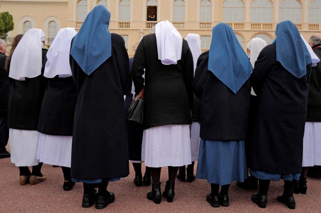 Nuns stand in front of Prince Albert II of Monaco and Princess Charlene of Monaco appearing on the balcony at the Place du Palais square during the traditional festivities of Sainte Devote in the Principalty of Monaco on January 27, 2026. (Photo by Valery HACHE / AFP) / NO TABLOIDS WEB & PRINT, NO DAILY MAIL, NO DAILY MAIL GROUP, NO VOICI, NO CLOSER