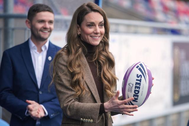 Britain's Catherine (R), Princess of Wales, holds a rugby ball during a visit to Wakefield Trinity Rugby League club in Wakefield, northern England on January 27, 2026, to learn how their outreach programmes bring generations together and support individuals experiencing isolation in the community. (Photo by Ian Hodgson / POOL / AFP)