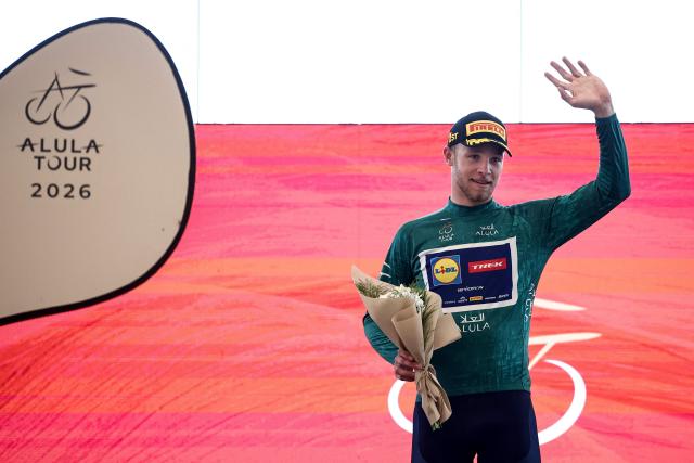 Lidl-Trek cycling team's Italian rider Jonathan Milan celebrates on the podium after winning the first stage of the AlUla Tour cycling race, a 158 km race started and finished in the Saudi desert city of AlUla, on January 27, 2026. (Photo by Anne-Christine POUJOULAT / AFP)