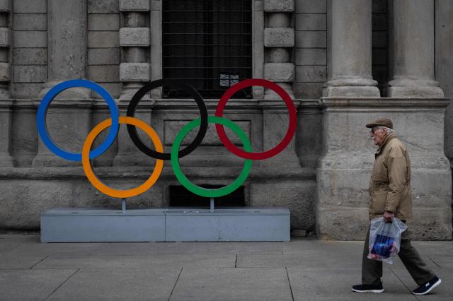 A man walks past the olympic rings ahead of Milano Cortina 2026 Olympic Games in Milan on January 27, 2026. (Photo by MARCO BERTORELLO / AFP)