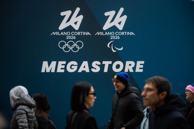 People walk past a banner of the Megastore for Milano Cortina 2026 Olympic Games at Piazza Duomo in Milan on January 27, 2026. (Photo by MARCO BERTORELLO / AFP)