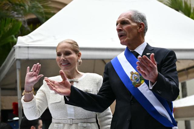 TOPSHOT - Honduras' President Nasry Asfura and his wife Lissette del Cid gesture from a stage following the inauguration ceremony at the Honduran Congress, in Tegucigalpa on January 27, 2026. Asfura, a conservative businessman elected with the support of US President Donald Trump, took office as president of Honduras with an agenda linked to the United States to address the economic and security challenges facing the most impoverished and violent country in Central America. (Photo by JOHAN ORDONEZ / AFP)
