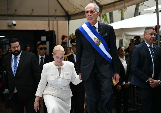 Honduras' President Nasry Asfura and his wife Lissette del Cid climb onto a stage following the inauguration ceremony at the Honduran Congress, in Tegucigalpa on January 27, 2026. Asfura, a conservative businessman elected with the support of US President Donald Trump, took office as president of Honduras with an agenda linked to the United States to address the economic and security challenges facing the most impoverished and violent country in Central America. (Photo by JOHAN ORDONEZ / AFP)