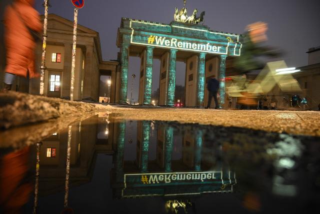 The slogan "We Remember" is projected with lights on the Branbenburg Gate as its reflection is seen on a water puddle in Berlin, Germany, on January 27, 2026, during commemorations of the International Holocaust Remembrance Day. (Photo by RALF HIRSCHBERGER / AFP)