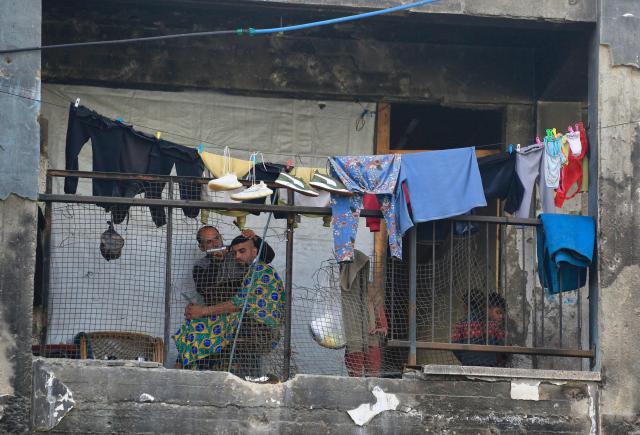 A Palestinian man receives a haircut from another on the balcony of a destroyed building by the Israeli military in Khan Yunis in the southern Gaza Strip on January 27, 2026. Since October 10, a fragile US-sponsored truce in Gaza has largely halted the fighting between Israeli forces and Hamas, but both sides have alleged frequent violations. (Photo by Bashar Taleb / AFP)