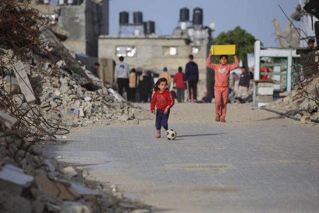 A Palestinian girl plays with a football in the street next to the rubble of destroyed buildings by the Israeli military in Khan Yunis in the southern Gaza Strip on January 27, 2026. Since October 10, a fragile US-sponsored truce in Gaza has largely halted the fighting between Israeli forces and Hamas, but both sides have alleged frequent violations. (Photo by Bashar Taleb / AFP)