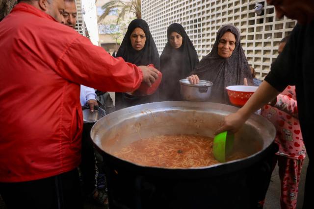 Palestinians gather to receive food portions in Khan Yunis in the southern Gaza Strip on January 27, 2026. Since October 10, a fragile US-sponsored truce in Gaza has largely halted the fighting between Israeli forces and Hamas, but both sides have alleged frequent violations. (Photo by Bashar Taleb / AFP)