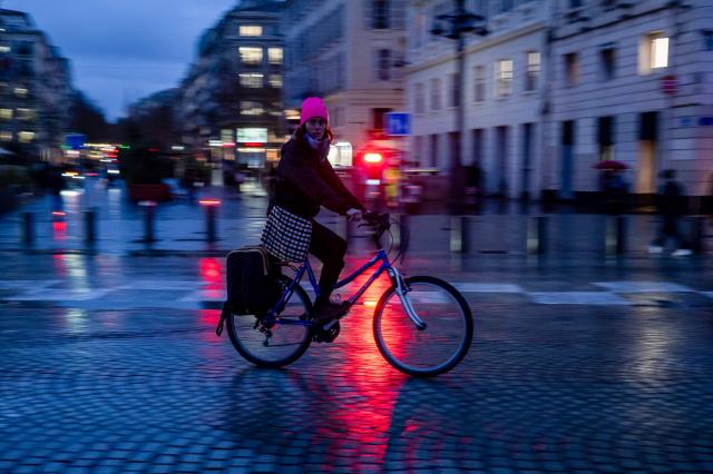A woman rides a bicycle on a rainy day at the Vieux Port in central Marseille, southern France on January 27, 2026. (Photo by Miguel MEDINA / AFP)