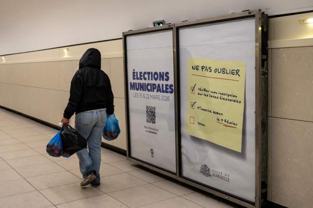 A pedestrian walks past a poster inviting citizens to vote for the upcoming municipal elections, in the subway of Marseille on January 27, 2026. (Photo by Miguel MEDINA / AFP)