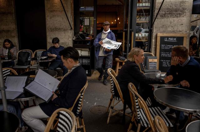 (FILES) Pakistani born 73-year-old newspaper hawker Ali Akbar sells newspaper copies in the street of the Latin Quarter in Paris on September 16, 2025. Akbar, the last remaining newspaper vendor of the French capital, will be awarded by France's President as knight in the National Order of Merit. (Photo by Guillaume BAPTISTE / AFP)