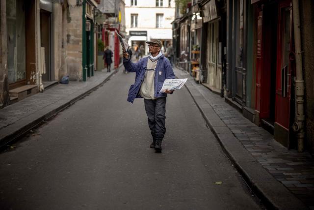 (FILES) Pakistani born 73-year-old newspaper hawker Ali Akbar sells newspaper copies in the street of the Latin Quarter in Paris on September 16, 2025. Akbar, the last remaining newspaper vendor of the French capital, will be awarded by France's President as knight in the National Order of Merit. (Photo by Guillaume BAPTISTE / AFP)