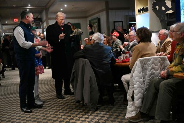 US President Donald Trump signs a hat during a stop at the Machine Shed restaurant in Urbandale, Iowa, on January 27, 2026. (Photo by Brendan SMIALOWSKI / AFP)