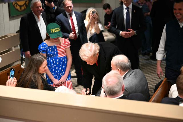 US President Donald Trump signs autographs during a stop at the Machine Shed restaurant in Urbandale, Iowa, on January 27, 2026. (Photo by Brendan SMIALOWSKI / AFP)