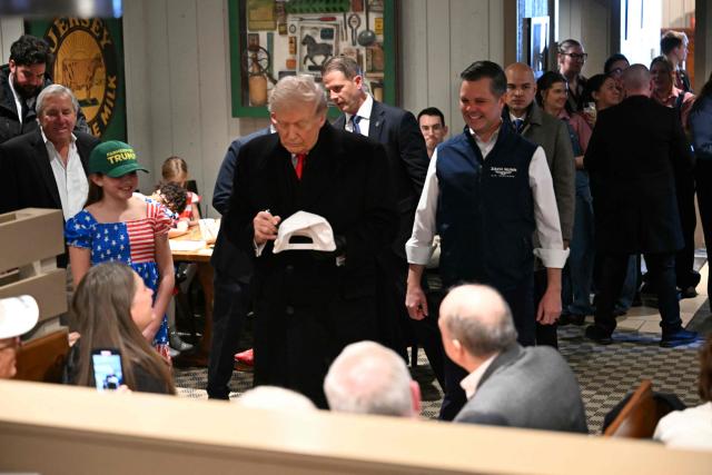 US President Donald Trump signs autographs during a stop at the Machine Shed restaurant in Urbandale, Iowa, on January 27, 2026. (Photo by Brendan SMIALOWSKI / AFP)