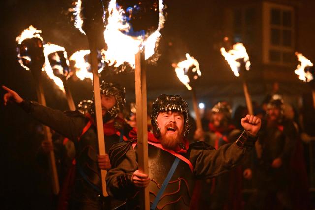 Members of the Up Helly Aa 'Jarl Squad' march with torches to set fire to their Viking galley longship, in Lerwick, Shetland Islands on January 27, 2026 during the Up Helly Aa festival. Up Helly Aa celebrates the influence of the Scandinavian Vikings in the Shetland Islands and culminates with up to 1,000 'guizers' (men in costume) throwing flaming torches into their Viking longboat and setting it alight later in the evening. (Photo by ANDY BUCHANAN / AFP)
