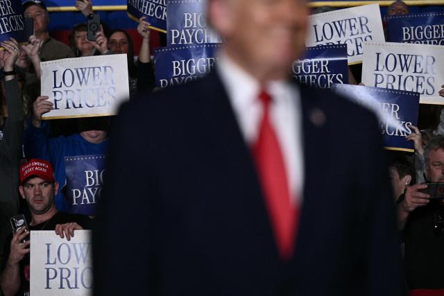 Attendees hold up signs as US President Donald Trump arrives to deliver remarks on the economy in Clive, Iowa, on January 27, 2026. (Photo by Brendan SMIALOWSKI / AFP)