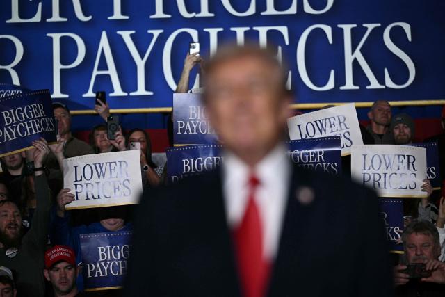 Attendees hold up signs as US President Donald Trump arrives to deliver remarks on the economy in Clive, Iowa, on January 27, 2026. (Photo by Brendan SMIALOWSKI / AFP)