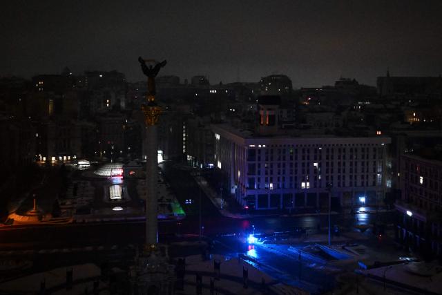 A police car with blue lights flashing patrols the darkened Independence Square during an air raid alert in Kyiv early on January 28, 2026, amid the Russian invasion of Ukraine.  (Photo by Sergei GAPON / AFP)