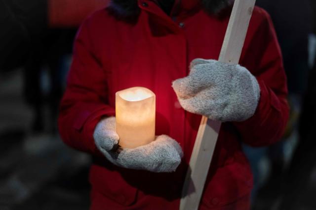 An anti-US Immigration and Customs Enforcement (ICE) protester wearing gloves holds a candle in downtown Minneapolis, Minnesota, on January 27, 2026. US President Donald Trump said on January 27 that he would "de-escalate a little bit" in Minneapolis after the fatal shootings of two civilians fueled a storm of criticism over his signature immigration crackdown. (Photo by ROBERTO SCHMIDT / AFP)