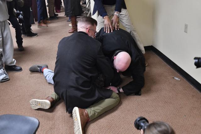 A man is tackled after spraying an unknown substance using a syringe (seen on the floor at R) at US Representative Ilhan Omar (D-MN) (out of frame) during a town hall she was hosting in Minneapolis, Minnesota, on January 27, 2026. US Democratic congresswoman Ilhan Omar was targeted during a speech late on January 27 by a man who sprayed an unidentified liquid at her from a syringe before being tackled by security guards, according to an AFP journalist at the scene. The man was led out of the premises as Omar, a frequent target of attacks by President Donald Trump, continued her speech saying "we will stay resilient in the face of whatever they might throw on us." (Photo by Octavio JONES / AFP)
