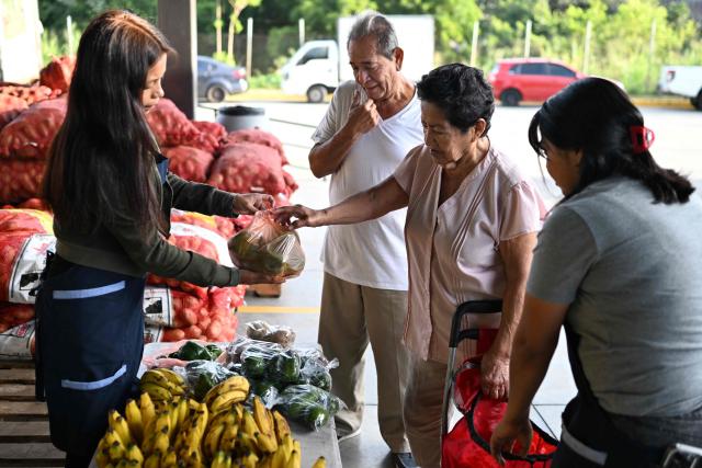 (FILES) People buy vegetables at the new food supply center on the day of its inauguration in Soyapango, El Salvador, on October 30, 2024. Most Salvadorans believe that their personal finances have deteriorated due to the cost of living in the country, to the point that it is now their greatest concern, ahead of security, according to a survey released on January 27, 2026. (Photo by Marvin RECINOS / AFP)