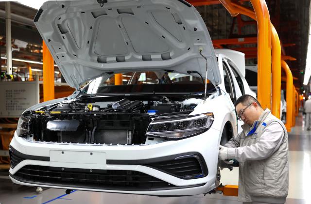 A worker assembles a vehicle on a production line at a FAW-Volkswagen factory in Qingdao, in China’s eastern Shandong province on January 27, 2026. (Photo by -STR / AFP) / China OUT
