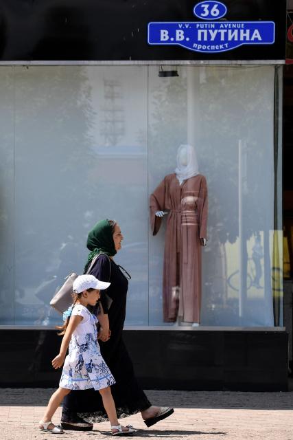 (FILES) A woman and a child walk past a shop selling Islamic clothes for women on an avenue named after Russian President Vladimir Putin in central Grozny on July 26, 2017. (Photo by Kirill KUDRYAVTSEV / AFP)