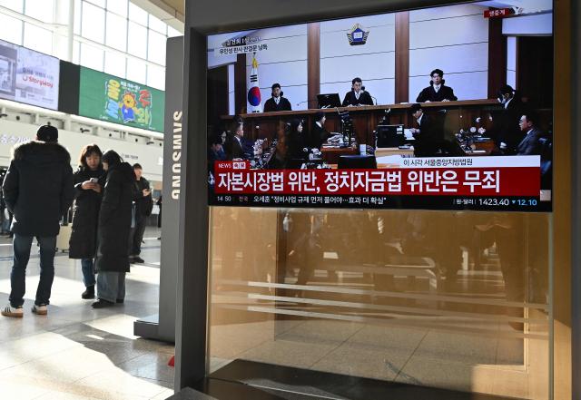 People stand next to a television screen showing a live broadcast of the trial verdict on corruption charges of South Korea's former first lady Kim Keon Hee (2nd R on the screen), at a train station in Seoul on January 28, 2026. A South Korean judge handed the country's former first lady Kim Keon Hee 20 months in jail for corruption on January 28, but acquitted her for alleged stock manipulation and other charges. (Photo by Jung Yeon-je / AFP)