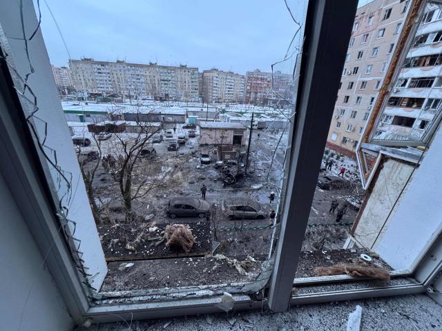 This photograph taken from a broken window shows burned cars and a damaged residential building following an air attack in Zaporizhzhia on January 28, 2026, amid the Russian invasion of Ukraine. (Photo by Darya NAZAROVA / AFP)