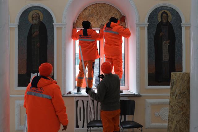 Communal workers cover a broken window of the Holy Dormition Monastery with a wooden plate following an air attack in Odesa on January 28, 2026, amid the Russian invasion of Ukraine. (Photo by Oleksandr GIMANOV / AFP)