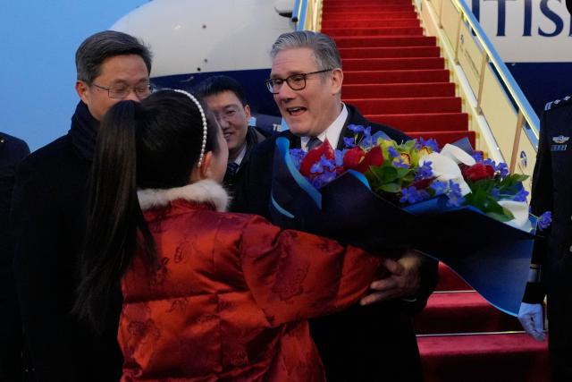 Britain's Prime Minister Keir Starmer receives a bouquet of flowers upon his arrival at an airport in Beijing on January 28, 2026. (Photo by Kin Cheung / POOL / AFP)