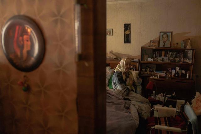 Esfir Rudminska, an 88-year-old pensioner, sits on a bed in her apartment without electricity and with almost no heating, in Kyiv on January 26, 2026, following missile and drone attacks on Ukrainian energy infrastructure amid the Russian invasion in Ukraine. Russia has this month stepped up its strikes against Ukraine's power and heating infrastructure, plunging Kyiv residents into darkness and cold as temperatures dropped as low as -20C. (Photo by Roman PILIPEY / AFP)