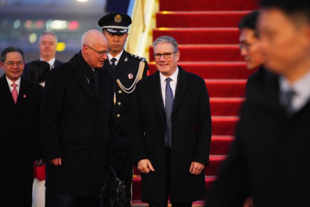 Britain's Prime Minister Keir Starmer (centre R) is welcomed upon his arrival at an airport in Beijing on January 28, 2026. British Prime Minister Keir Starmer arrived in Beijing on January 28 to meet with Chinese leader Xi Jinping, hoping to restore long fraught relations. (Photo by Carl Court / POOL / AFP)