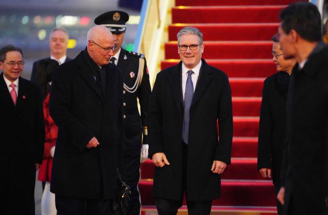 Britain's Prime Minister Keir Starmer (centre R) is welcomed upon his arrival at an airport in Beijing on January 28, 2026. British Prime Minister Keir Starmer arrived in Beijing on January 28 to meet with Chinese leader Xi Jinping, hoping to restore long fraught relations. (Photo by Carl Court / POOL / AFP)