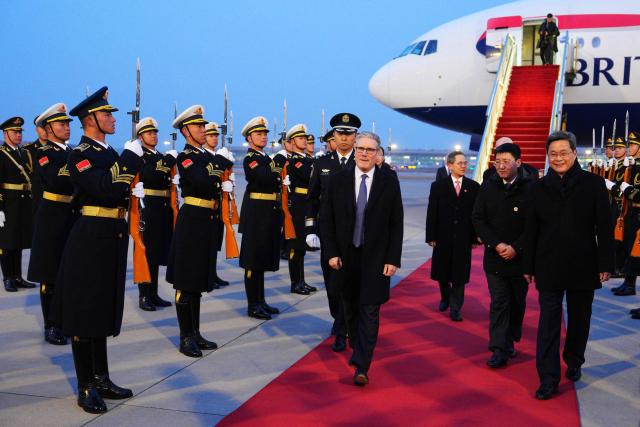 TOPSHOT - Britain's Prime Minister Keir Starmer (C) is welcomed upon his arrival at an airport in Beijing on January 28, 2026. British Prime Minister Keir Starmer arrived in Beijing on January 28 to meet with Chinese leader Xi Jinping, hoping to restore long fraught relations. (Photo by Carl Court / POOL / AFP)