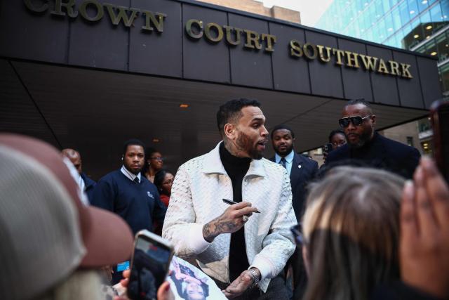 US R&B singer Chris Brown (C) signs autographs as he departs from the Southwark Crown Court in London on January 28, 2026. Brown returned to the UK court after pleading not guilty in July 2025 on further charges stemming from an alleged London nightclub brawl in 2023. (Photo by Henry NICHOLLS / AFP)