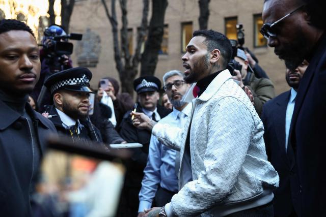 US R&B singer Chris Brown (R) walks past fans and police as he departs from the Southwark Crown Court in London on January 28, 2026. Brown returned to the UK court after pleading not guilty in July 2025 on further charges stemming from an alleged London nightclub brawl in 2023. (Photo by Henry NICHOLLS / AFP)