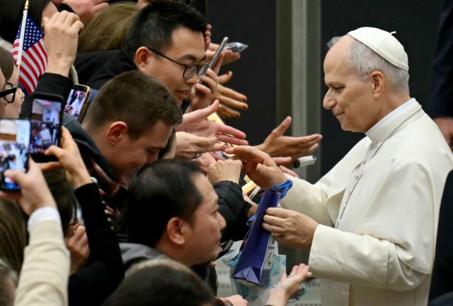 Faithfuls greets Pope Leo XIV's cross during his weekly general audience inside Paul VI hall at the Vatican on January 28, 2026. (Photo by Filippo MONTEFORTE / AFP)
