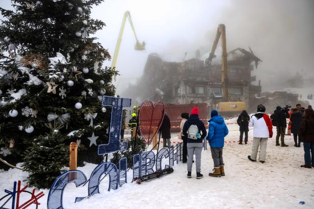People watch as firefighters work on a fire that broke out the evening before at the five-star Grandes Alpes hotel in the upscale French Alpine ski resort of Courchevel, forcing the evacuation of 83 occupants, on January 28, 2026. More than a hundred firefighters were still working on January 28 morning to bring under control the violent fire, which origin remains undetermined, and nearly 300 people were evacuated. (Photo by Alex MARTIN / AFP)
