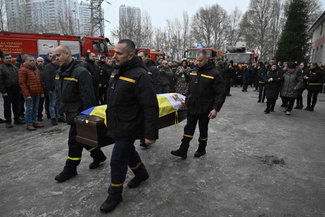 Rescuers carry the coffin of their colleague Oleksandr Zibrov during  a farewell ceremony in Kyiv on January 28, 2026, amid the Russian invasion of Ukraine. Oleksandr Zibrov, firefighter-rescuer of the 24th State Fire and Rescue Unit passed away on January 26 - after 18 days fighting for his life. He sustained severe injuries on January 9 in Kyiv’s Darnytsia district during a repeated enemy strike, while carrying out his duties. (Photo by Genya SAVILOV / AFP)