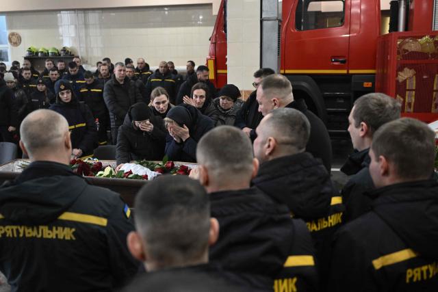 Relatives mourn over the coffin of rescuer Oleksandr Zibrov during  a farewell ceremony in Kyiv on January 28, 2026, amid the Russian invasion of Ukraine. Oleksandr Zibrov, firefighter-rescuer of the 24th State Fire and Rescue Unit passed away on January 26 - after 18 days fighting for his life. He sustained severe injuries on January 9 in Kyiv’s Darnytsia district during a repeated enemy strike, while carrying out his duties. (Photo by Genya SAVILOV / AFP)