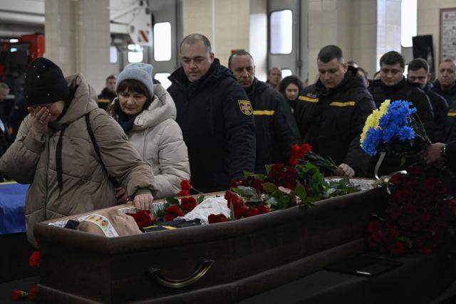 Colleagues and friends pay last respect to rescuer Oleksandr Zibrov during farewell ceremony in Kyiv on January 28, 2026, amid the Russian invasion of Ukraine. Oleksandr Zibrov, firefighter-rescuer of the 24th State Fire and Rescue Unit passed away on January 26 - after 18 days fighting for his life. He sustained severe injuries on January 9 in Kyiv’s Darnytsia district during a repeated enemy strike, while carrying out his duties. (Photo by Genya SAVILOV / AFP)