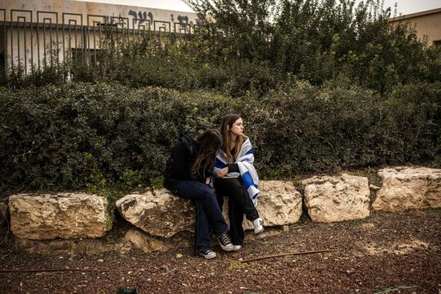 TOPSHOT - Women, one of them wearing the Israeli flag around her shoulders, mourn during the funeral of Israeli hostage Ran Gvili, whose remains were finally brought back to Israel on January 26, in the southern town of Meitar on January 28, 2026. Grieving relatives of Ran Gvili gathered on January 28, 2026, as Israel prepared to bury the last hostage returned from Gaza, marking the end of a painful national saga triggered by Hamas's 2023 attack. Israeli forces on January 26 brought home the remains of Gvili, a police officer who was killed in action during Hamas's attack on October 7, 2023 which triggered the devastating war in Gaza. (Photo by JOHN WESSELS / AFP)