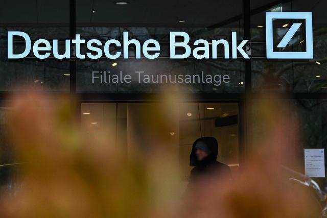 A passer-by walks past Deutsche Bank headquarters in Frankfurt am Main, on January 28, 2028, as German prosecutors and police on searched the bank's headquarters in an investigation over suspected money laundering offences, officials said. According to the Sueddeutsche Zeitung newspaper, the probe is connected to suspected offences in the bank's dealings with companies linked to Russian billionaire businessman Roman Abramovich. Prosecutors confirmed the raids but did not say who was being targeted. (Photo by Kirill KUDRYAVTSEV / AFP)