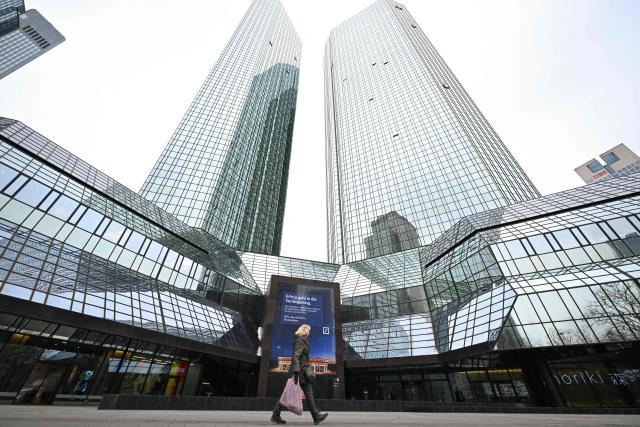 A woman walks past Deutsche Bank headquarters in Frankfurt am Main, on January 28, 2028, as German prosecutors and police on searched the bank's headquarters in an investigation over suspected money laundering offences, officials said. According to the Sueddeutsche Zeitung newspaper, the probe is connected to suspected offences in the bank's dealings with companies linked to Russian billionaire businessman Roman Abramovich. Prosecutors confirmed the raids but did not say who was being targeted. (Photo by Kirill KUDRYAVTSEV / AFP)