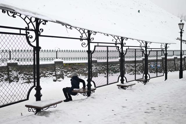 A woman exercises in a snowy park in Kyiv on January 28, 2026, amid the Russian invasion of Ukraine. (Photo by Sergei GAPON / AFP)