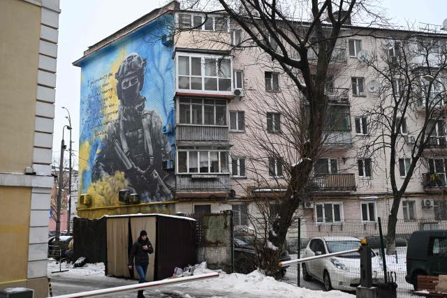 A pedestrian walks past a residential building with a patriotic mural depicting a Ukrainian soldier in Kyiv on January 28, 2026, amid the Russian invasion of Ukraine. (Photo by Sergei GAPON / AFP)