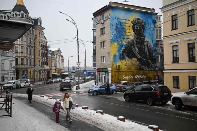 Pedestrians walk past a residential building with a patriotic mural depicting a Ukrainian soldier in Kyiv on January 28, 2026, amid the Russian invasion of Ukraine. (Photo by Sergei GAPON / AFP)