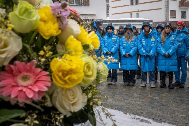 Members of the Italy's alpine skiing team taking part in the World Cup races in Crans Montana, with Women's Technical Director Gianluca Rulfi (R), and Sofia Goggia (2nd R) stand in front of the bar "Le Constellation" to pay tribute to the victims of the fire that ripped through the venue on New Year's Eve celebrations, in the Alpine ski resort of Crans-Montana on January 28, 2026. The fire on January 1 at the bar "Le Constellation" left 40 people dead -- including nine French and six Italian nationals -- and injured 116 others, most of them teenagers. (Photo by Fabrice COFFRINI / AFP)